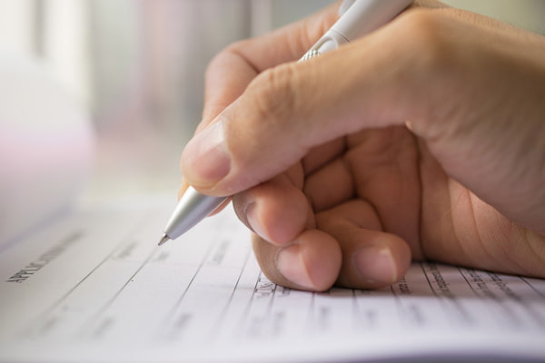 Hand with pen over application form